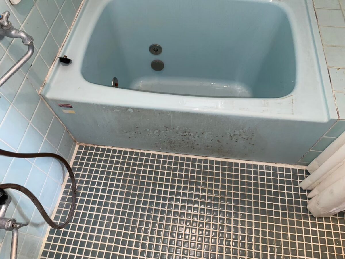 施工前、水色のホーロー浴槽を正面から見たところ。前面に黒っぽい点状の汚れがある