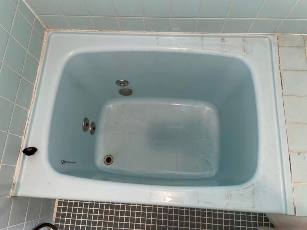 施工前、水色のホーロー浴槽を真上から見たところ。ふちに擦れた跡と汚れがある
