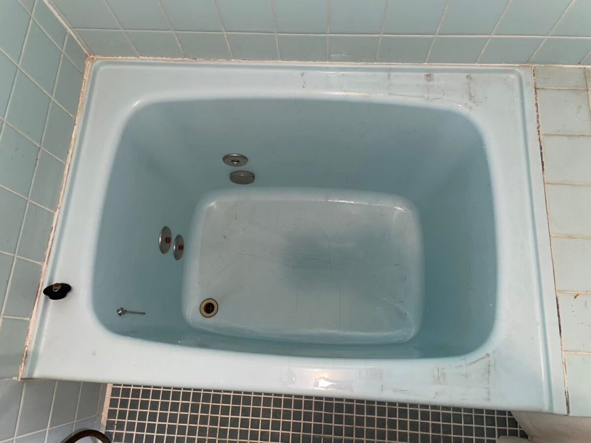 施工前、水色のホーロー浴槽を真上から見たところ。ふちに擦れた跡と汚れがある