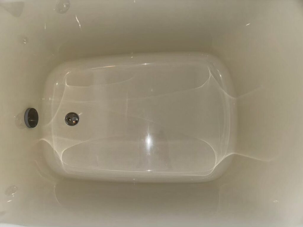 施工後、浴槽の内側の底を真上から近くで見たところ。なめらかなライトアイボリーの面