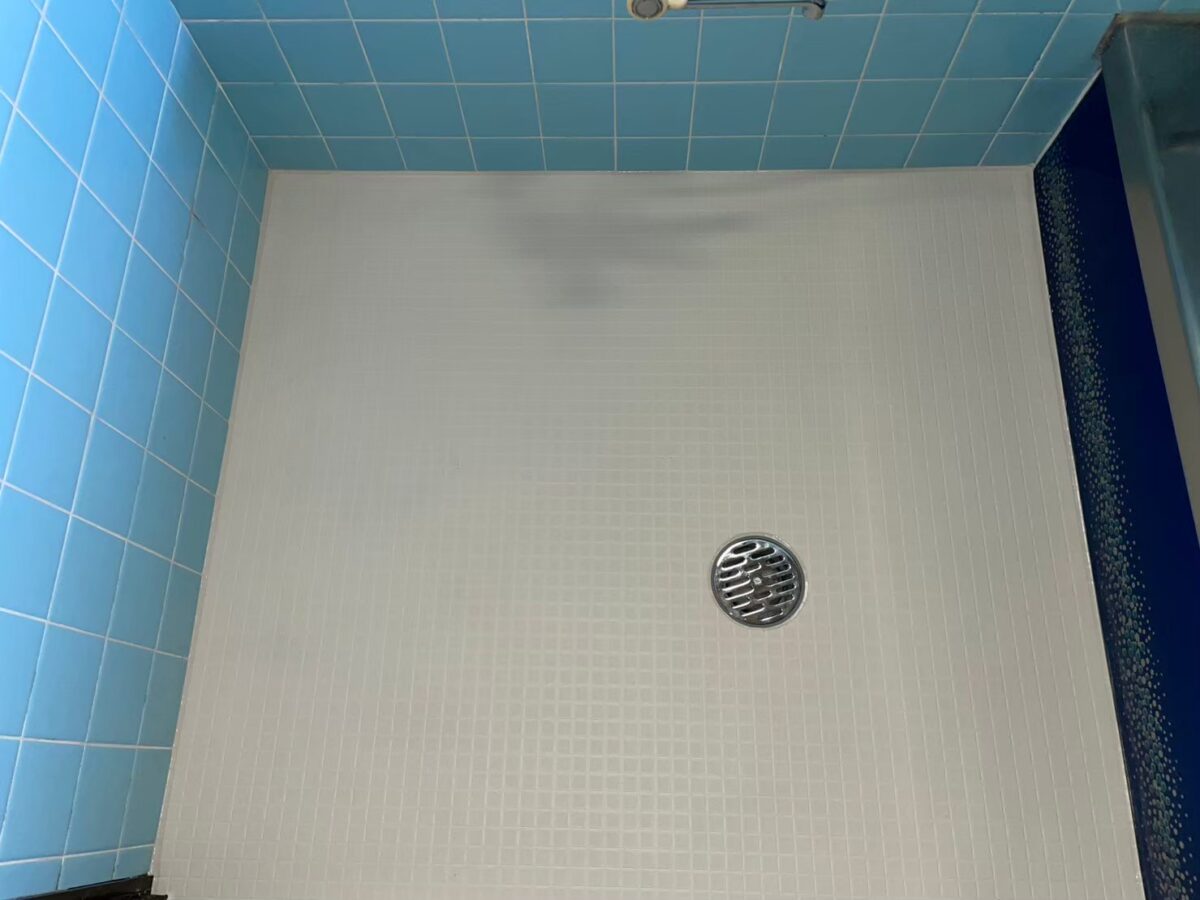 施工後、床シートを施工した床。排水口のまわりと、水色のタイルの壁