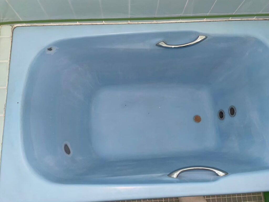 施工前、水色のホーロー浴槽を真上から見たところ。表面がくすみ、底の近くに茶色い点がある
