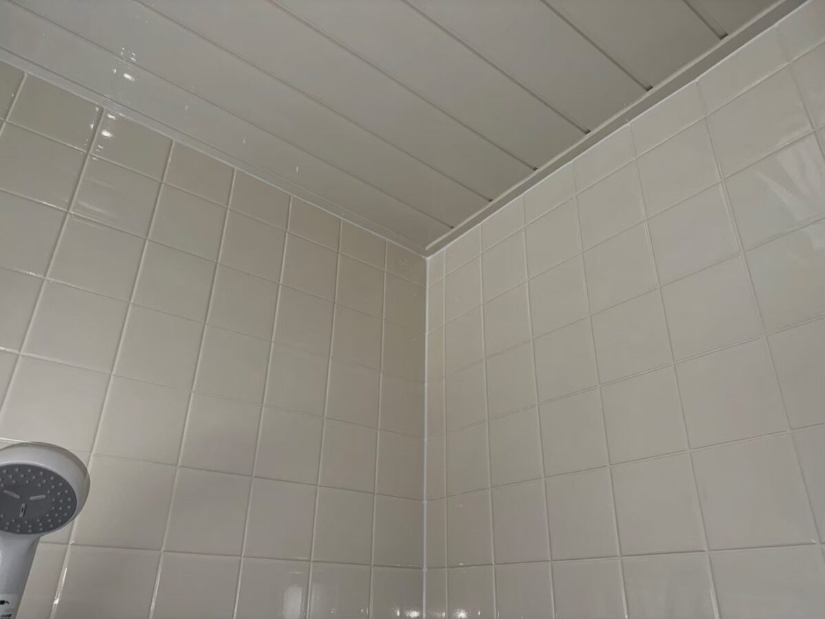 施工後、壁と天井の隅。白いタイルと白い板張りの天井