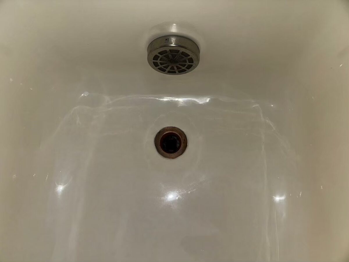 施工後、浴槽の排水口のまわり。ライトアイボリーでつやがある