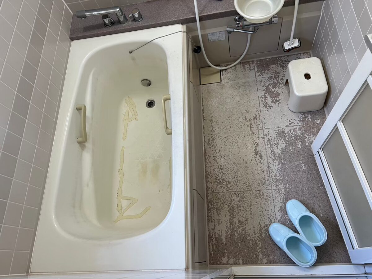 加東市の施工前、浴槽の底に補修跡が残り、床の表面がまだらにすり減っている浴室