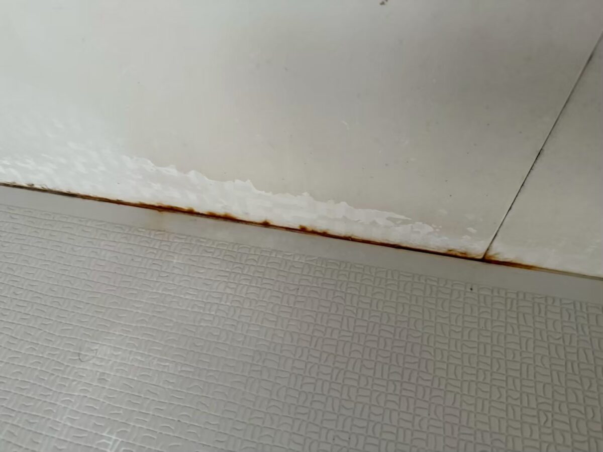施工前、壁と床の境目。赤茶色の線のような汚れが続き、その上に白くざらついた跡がある