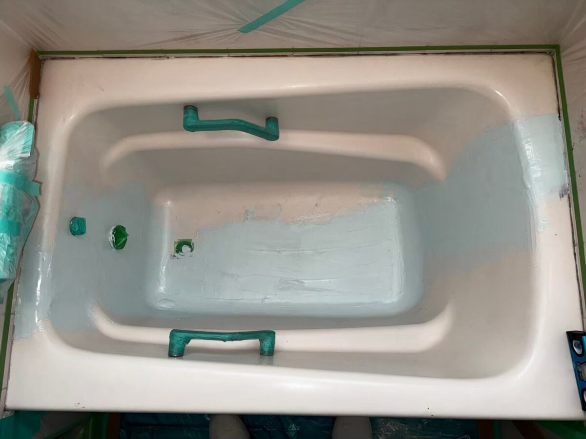 施工の途中、ベースコートを吹き付けている浴槽。塗った部分が白っぽい色に変わっている