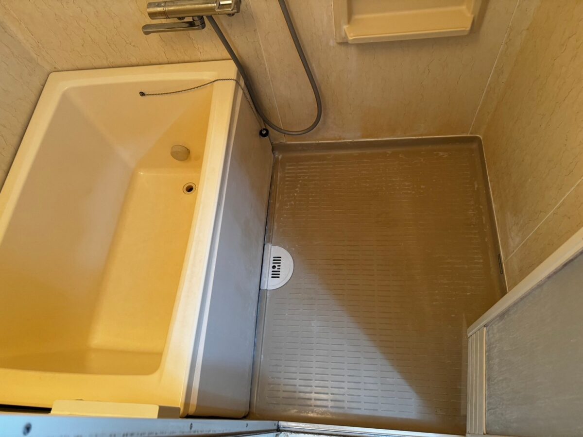 施工前、浴槽の前面と洗い場の床を少し近づいて見たところ。床にはすべり止めの溝が並び、白っぽい汚れが残っている