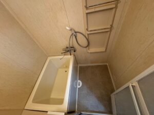 施工後、同じ角度から見た浴室。浴槽が明るいアイボリー色になり、洗い場の床が濃い色の床シートになっている