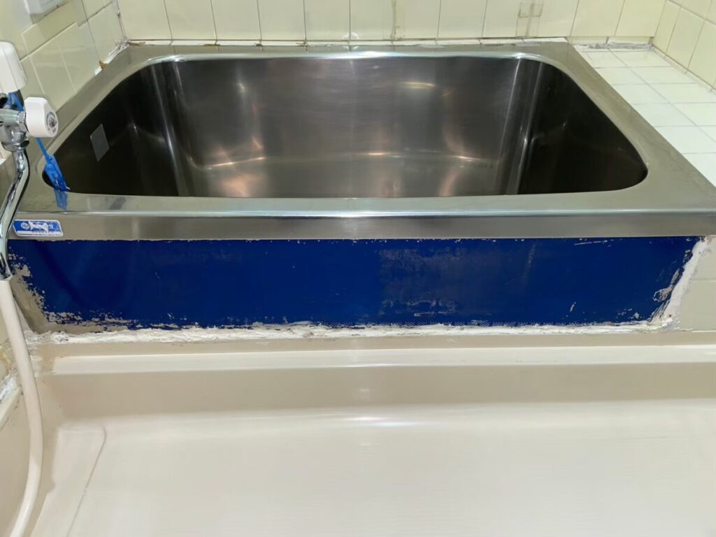 施工前、ステンレス浴槽の前面。紺色の塗装が剥がれている