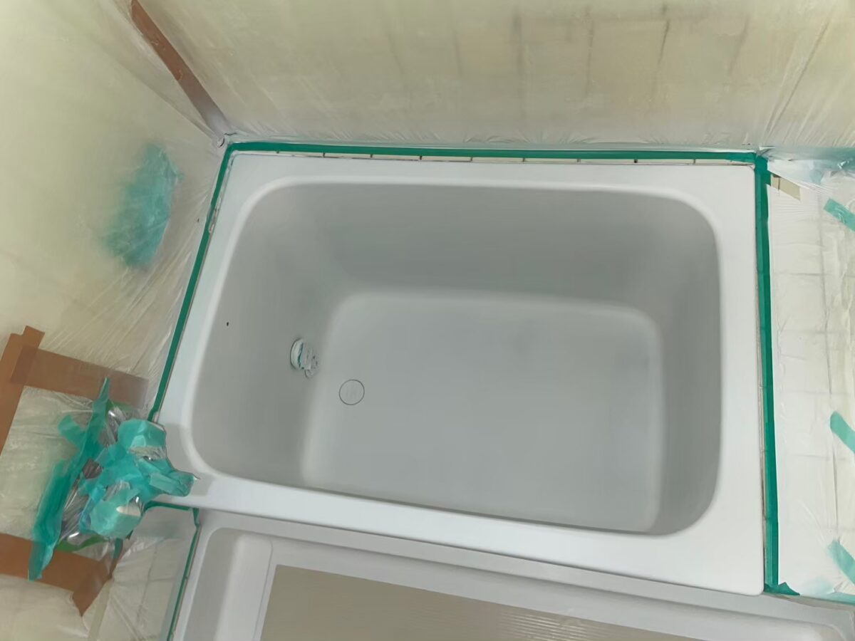 ベースコートを吹き付けたステンレス浴槽。まわりを養生している