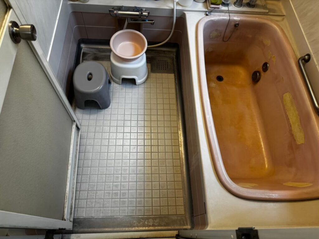 施工前、入口側から見た浴室。右側のカラーステンレス浴槽は、ピンク色の面にオレンジがかった色の部分が広がっている