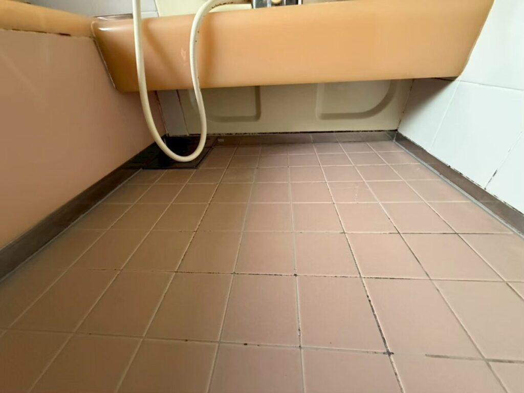 施工前、床とカウンターの下まわり。ピンクがかった小さな角タイルの床で、ところどころ目地が黒っぽい