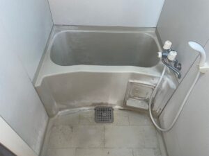小野市の施工前、ユニットバスを入口側から見たところ。浴槽のふちや洗い場の立ち上がりがくすみ、床には茶色いシミや黒ずみが広がっている