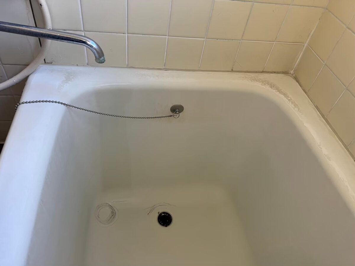 施工前、水栓側から見た浴槽の内側。ふちの内側の端が白く粗れている