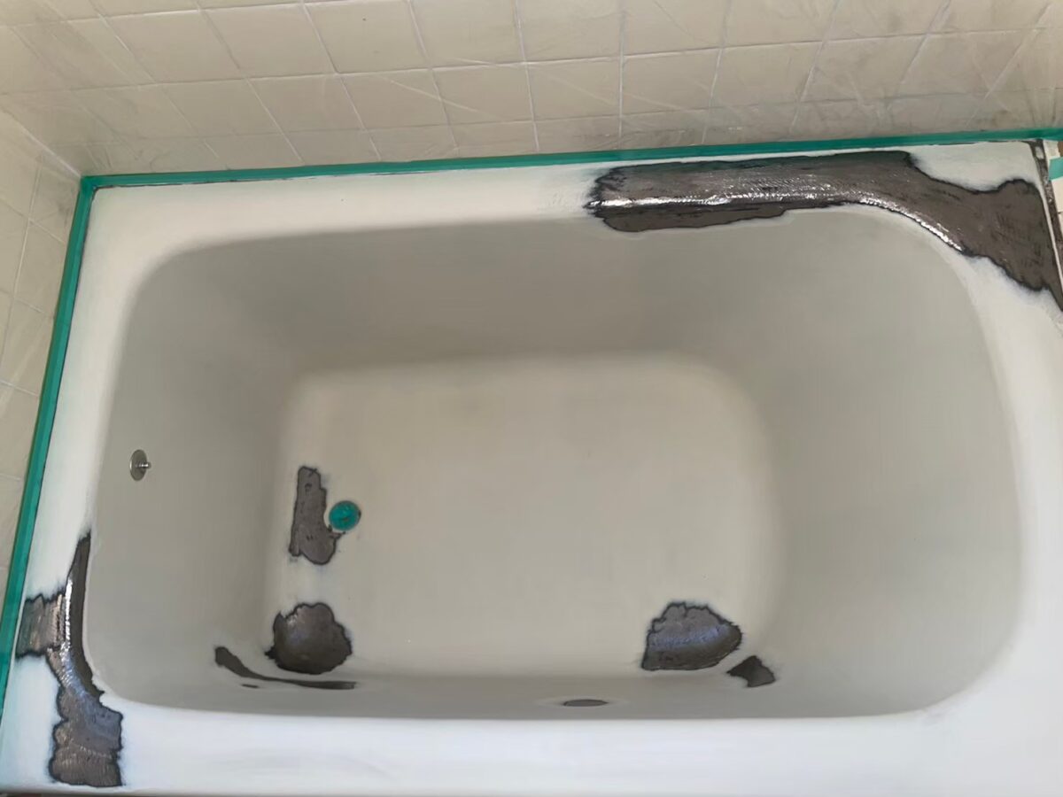 施工の途中。まわりを緑のテープで養生し、浴槽の表面に灰色の部分がまだらに見える
