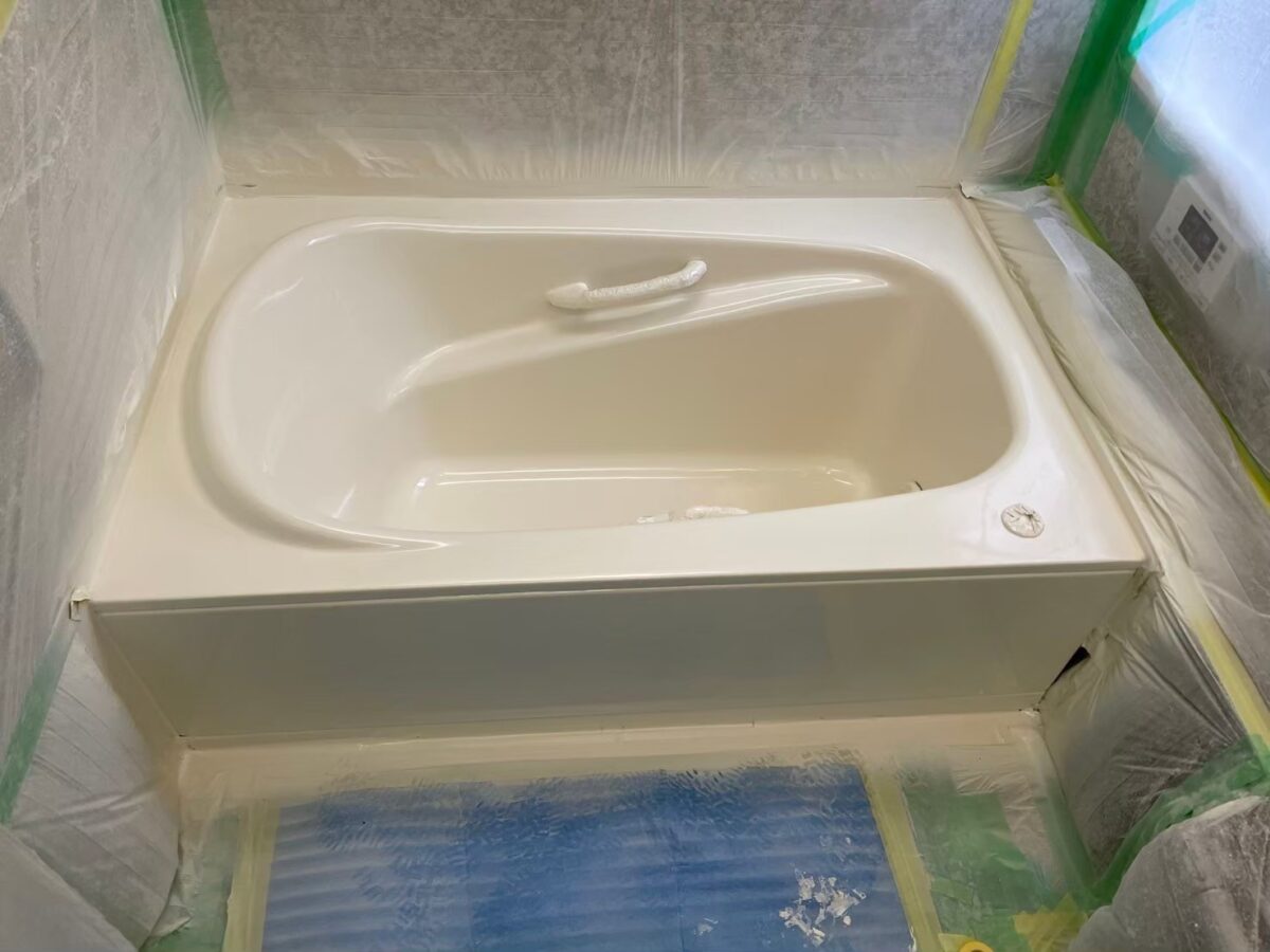 工程の途中、浴槽がクリーム色になり、つやが出てきた状態。養生ビニールとテープが残っている