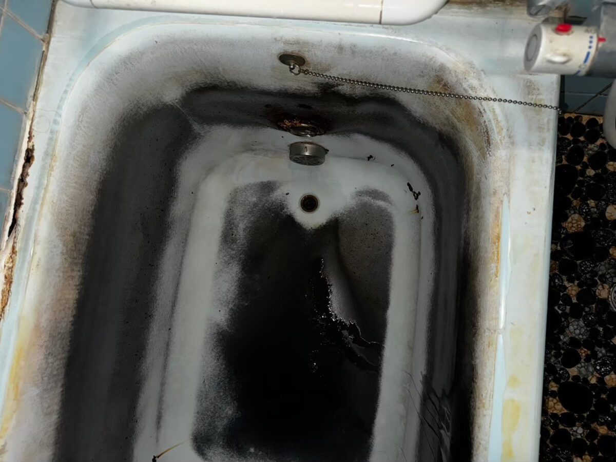 施工前、水栓側から浴槽の内側を見たところ。底から壁にかけて黒い汚れが広がっている