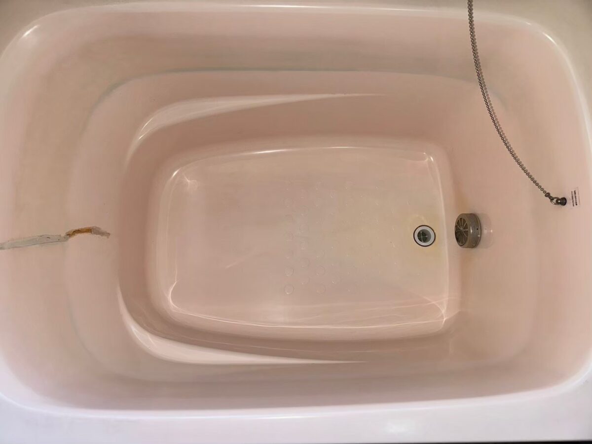 施工前、ピンク色の浴槽の内側を近くから見たところ。左側にひび割れの線がある