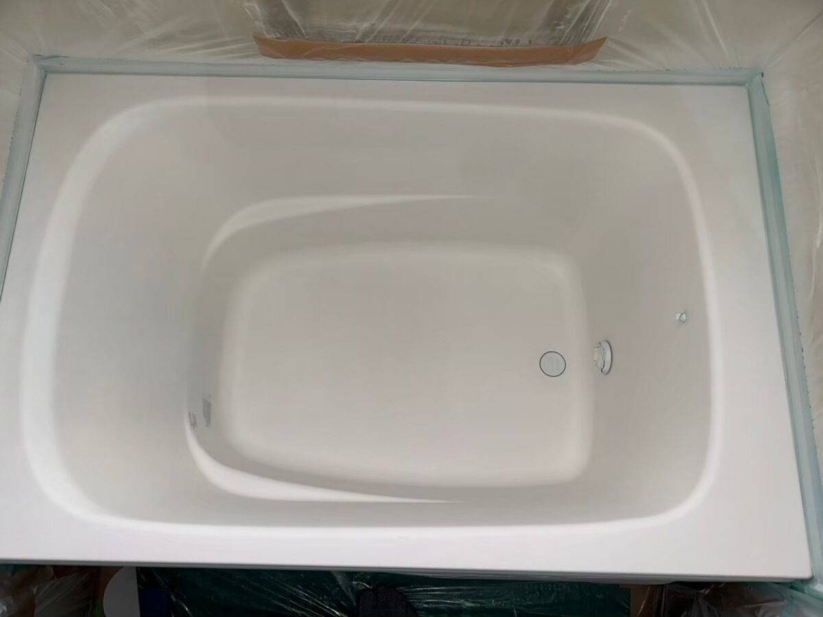 施工の途中、ベースコートを吹き付けた浴槽。まわりをビニールとテープで養生している