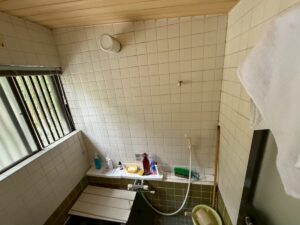 施工前、窓のほうから見た浴室。上は白いタイルの壁、下は緑色のタイル、天井は木目の板張り