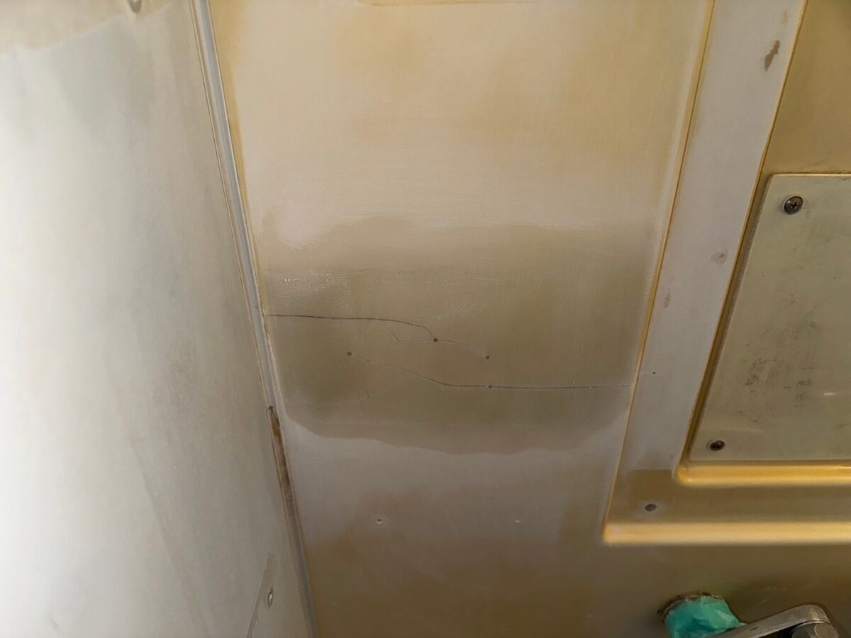 工程、壁のパネルを横に走る細い線。ひび割れのように見え、線の先に点状の印がある。帯状の部分には網目のような質感が見える